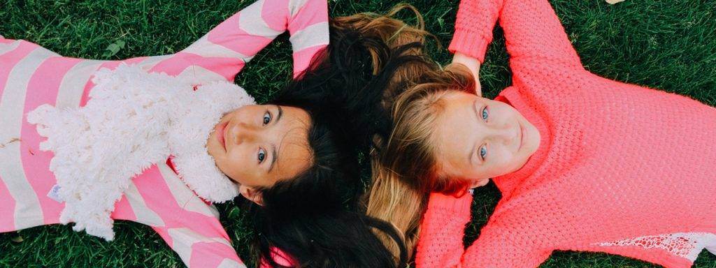 Young-Girls-Laying-on-Grass-1280x480-1024x384-1